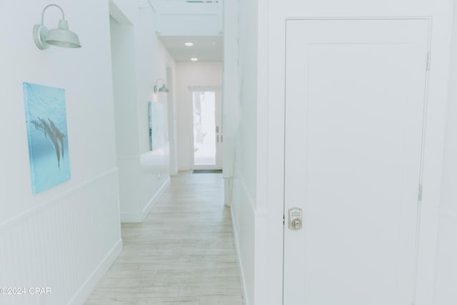 corridor featuring a wainscoted wall and light wood-style flooring