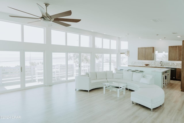 living area with light wood-type flooring, visible vents, and a towering ceiling