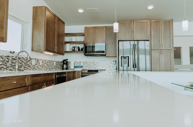 kitchen featuring a sink, light countertops, appliances with stainless steel finishes, open shelves, and decorative light fixtures