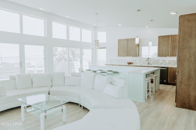 living area with recessed lighting, a healthy amount of sunlight, light wood-style flooring, and a high ceiling