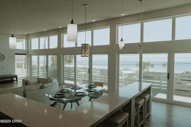 dining area with a water view, wood finished floors, a towering ceiling, and recessed lighting