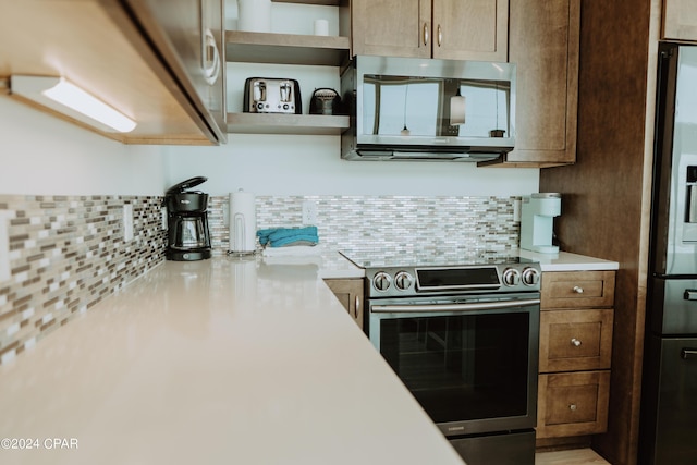 kitchen with brown cabinets, open shelves, stainless steel appliances, light countertops, and decorative backsplash