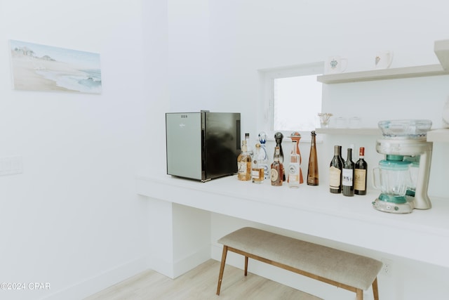 room details with a bar, baseboards, wood finished floors, and refrigerator