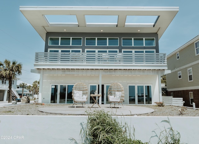 rear view of property with a balcony, a patio, and stucco siding