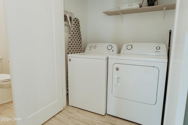 washroom featuring laundry area, light wood-style flooring, and separate washer and dryer