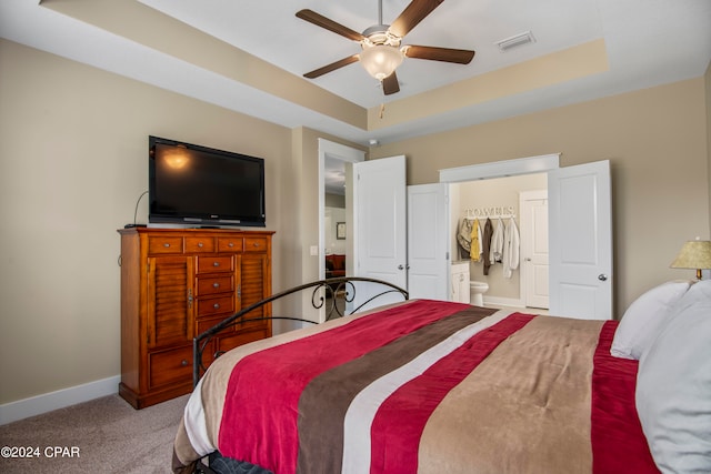 carpeted bedroom featuring a closet, ceiling fan, and a tray ceiling