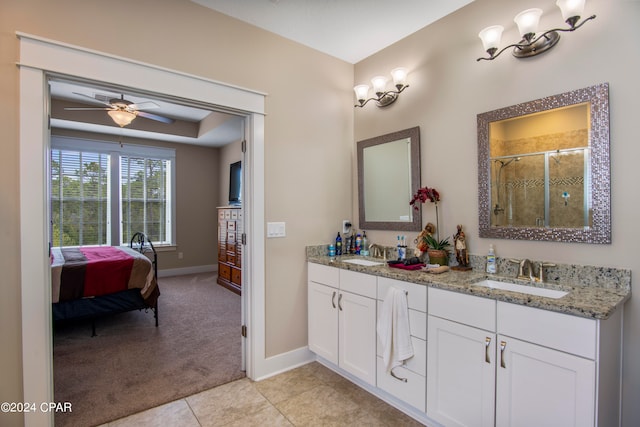 bathroom featuring double sink, ceiling fan, tile flooring, a raised ceiling, and vanity with extensive cabinet space