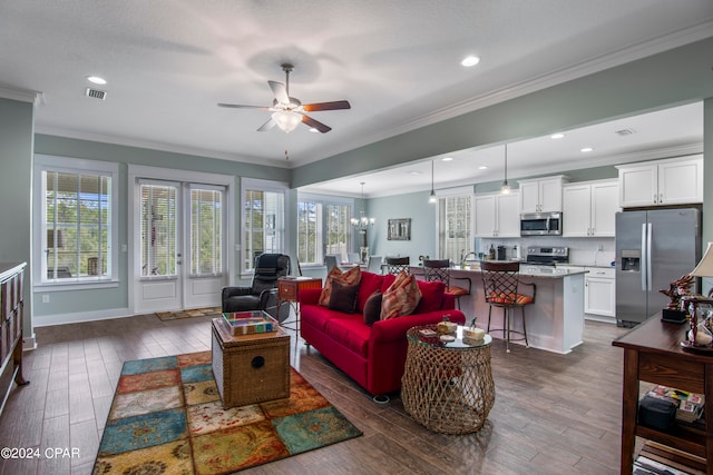 living room featuring french doors, dark hardwood / wood-style flooring, ceiling fan with notable chandelier, and ornamental molding