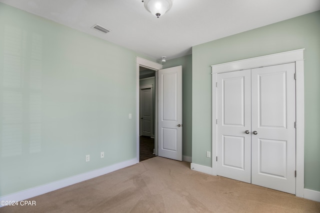 unfurnished bedroom featuring light carpet and a closet