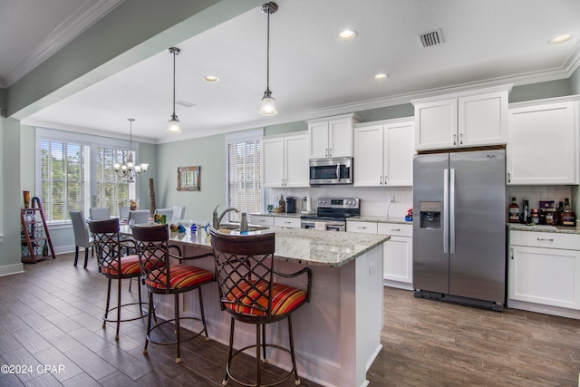 kitchen with a kitchen island with sink, pendant lighting, dark hardwood / wood-style flooring, stainless steel appliances, and an inviting chandelier