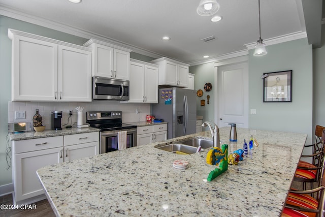 kitchen featuring white cabinets, a kitchen breakfast bar, decorative light fixtures, and appliances with stainless steel finishes