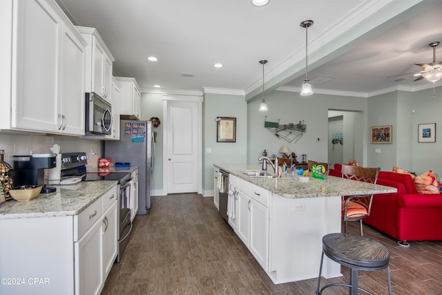 kitchen with pendant lighting, stainless steel appliances, ceiling fan, a breakfast bar area, and white cabinetry