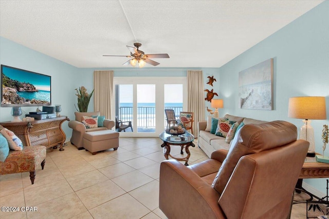 living room with light tile floors, a textured ceiling, ceiling fan, and a water view