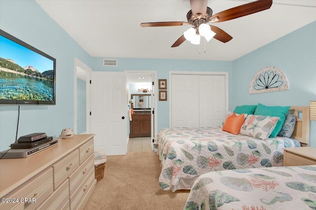 carpeted bedroom featuring ceiling fan, ensuite bath, and a closet