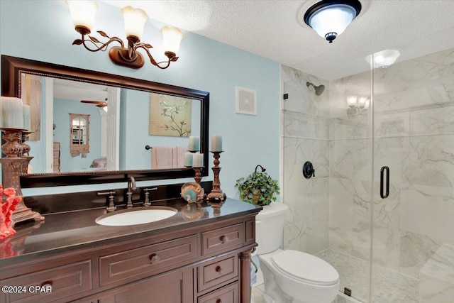 bathroom featuring toilet, vanity, a shower with shower door, and a textured ceiling