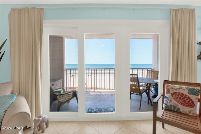 doorway with a water view, a view of the beach, and light tile floors