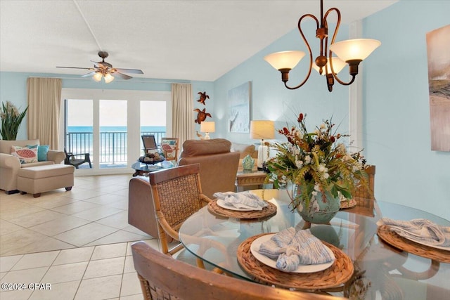 dining space featuring a water view, light tile floors, a textured ceiling, and ceiling fan with notable chandelier