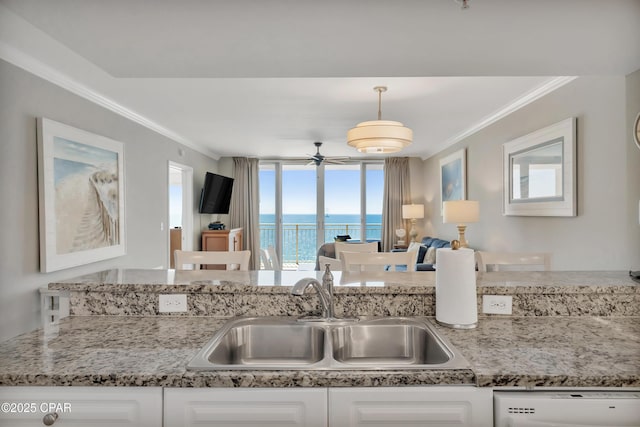 kitchen featuring dishwashing machine, light stone counters, a sink, white cabinets, and crown molding