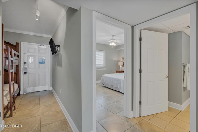 corridor with light tile patterned floors, visible vents, crown molding, and baseboards