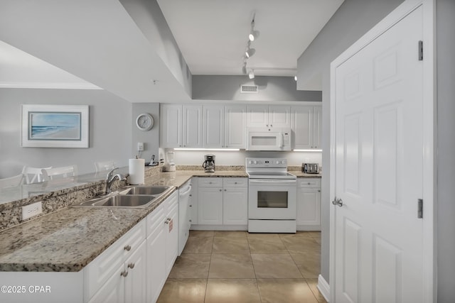 kitchen with a sink, light stone counters, white appliances, white cabinets, and light tile patterned flooring