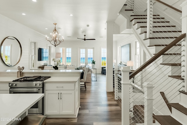 kitchen with pendant lighting, ceiling fan with notable chandelier, ornamental molding, high end stainless steel range, and dark hardwood / wood-style floors