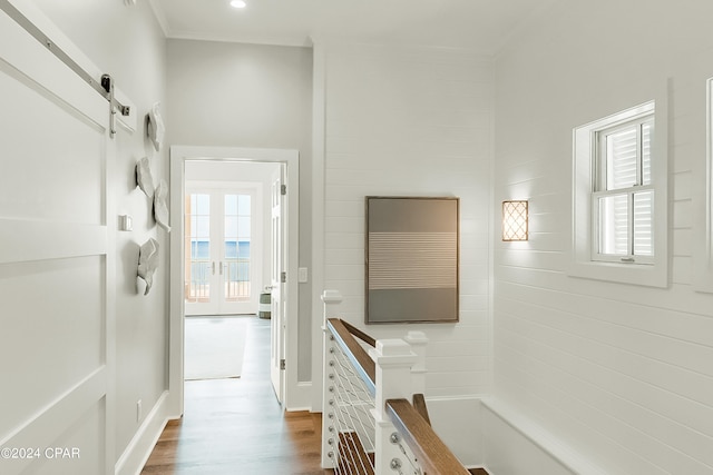 hallway with hardwood / wood-style flooring, crown molding, a barn door, and a healthy amount of sunlight