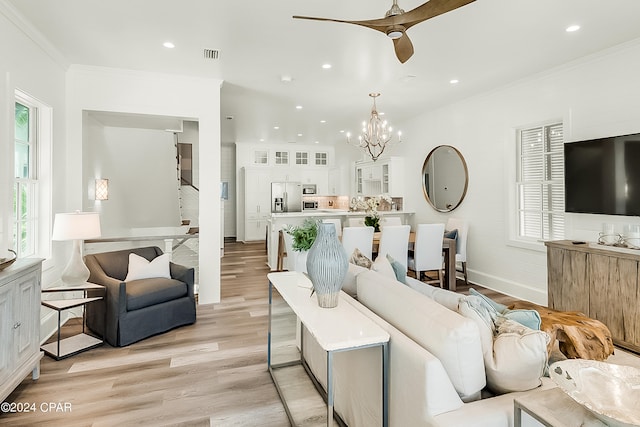 living room featuring crown molding, ceiling fan with notable chandelier, and light hardwood / wood-style flooring