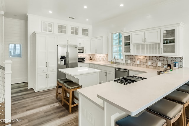 kitchen with white cabinets, a kitchen bar, tasteful backsplash, and light hardwood / wood-style flooring