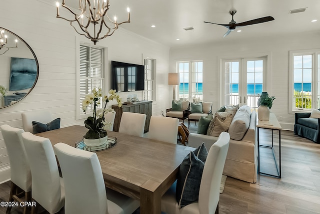 dining room featuring a water view, dark wood-type flooring, and ceiling fan with notable chandelier