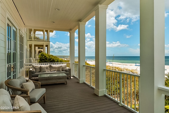 deck with a water view, a beach view, and an outdoor living space