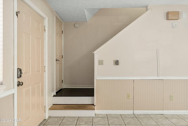 stairs featuring a textured ceiling and tile flooring