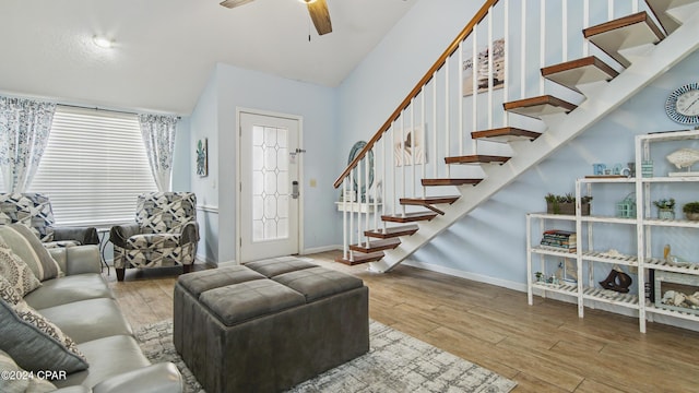 living area with ceiling fan, stairs, baseboards, and wood finished floors