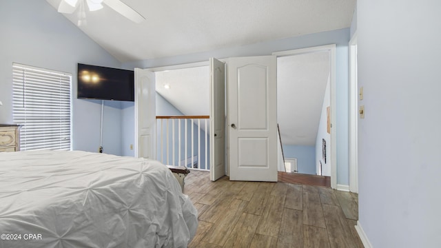 bedroom featuring ceiling fan, vaulted ceiling, baseboards, and wood finished floors