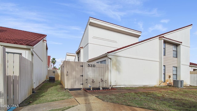 view of home's exterior featuring central air condition unit, a gate, fence, and stucco siding