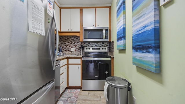 kitchen featuring appliances with stainless steel finishes, light countertops, white cabinetry, and backsplash