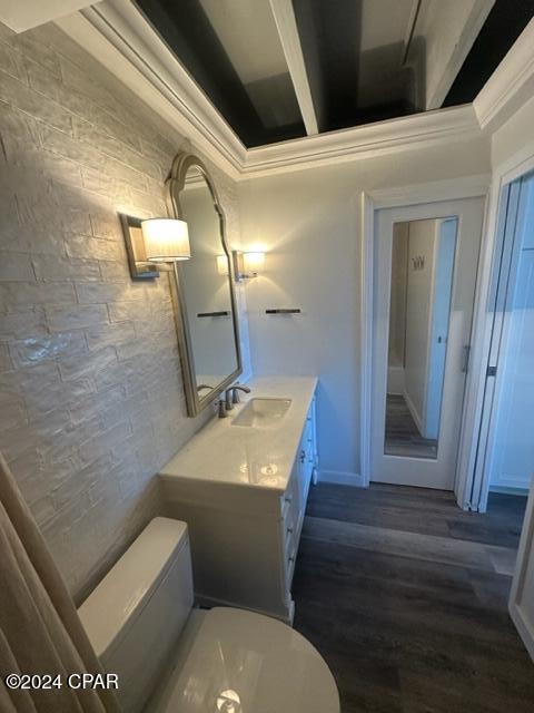 bathroom with wood-type flooring, vanity, toilet, and crown molding