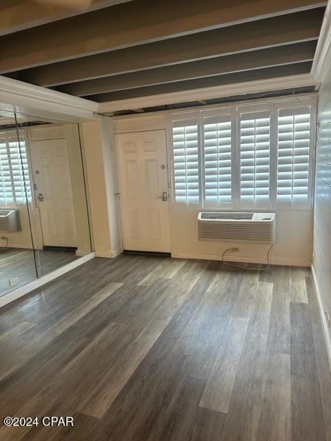 entrance foyer with hardwood / wood-style floors, a wall unit AC, a wealth of natural light, and beam ceiling