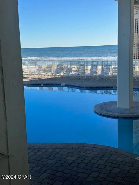 view of pool featuring a water view and a view of the beach