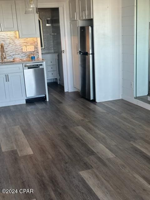 kitchen featuring pendant lighting, dark wood-type flooring, decorative backsplash, appliances with stainless steel finishes, and white cabinetry