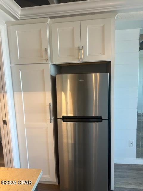 interior details featuring stainless steel refrigerator, white cabinetry, and wood-type flooring