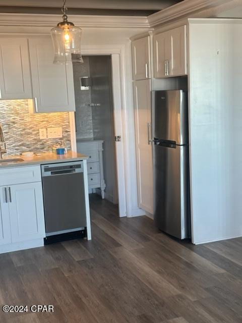 kitchen featuring white cabinetry, sink, dark hardwood / wood-style flooring, decorative light fixtures, and appliances with stainless steel finishes