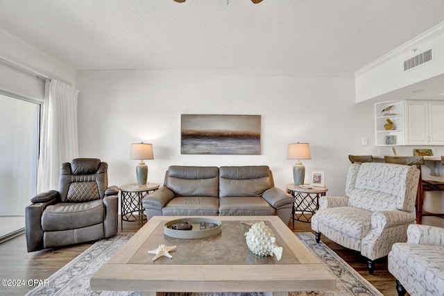 living room with a textured ceiling, hardwood / wood-style floors, and ornamental molding