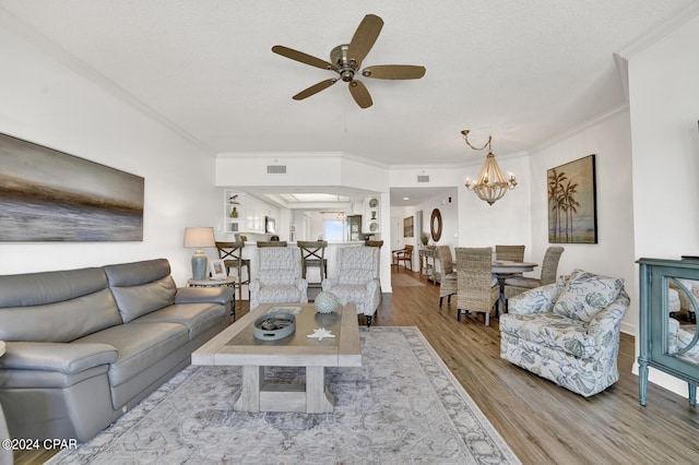 living room featuring ornamental molding, ceiling fan with notable chandelier, and light wood-type flooring