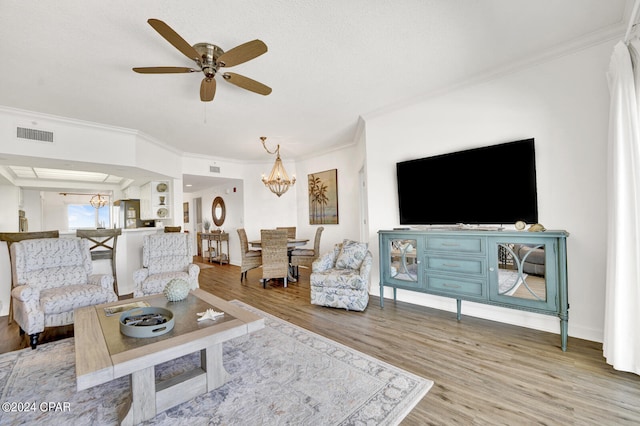 living room with ceiling fan with notable chandelier, light hardwood / wood-style floors, and crown molding