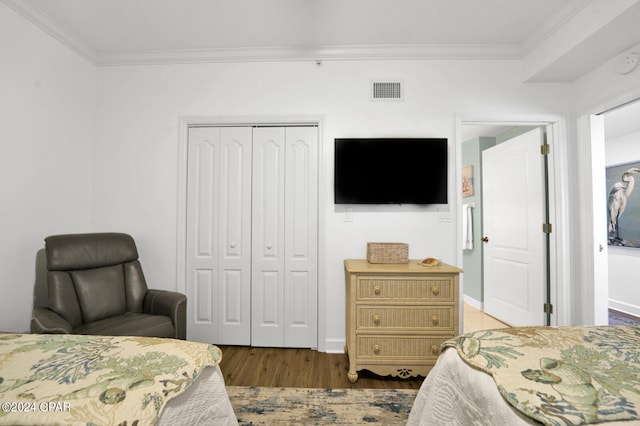 bedroom with crown molding, dark hardwood / wood-style flooring, and a closet