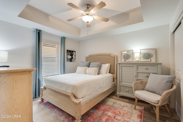 bedroom featuring hardwood / wood-style floors, ceiling fan, a raised ceiling, and a closet