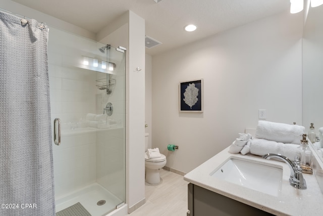 bathroom featuring vanity, toilet, and a shower with door