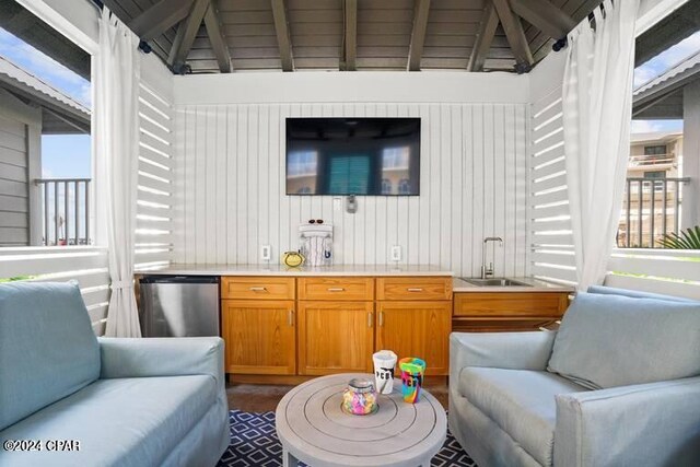 bar with stainless steel fridge, wooden walls, sink, and vaulted ceiling with beams