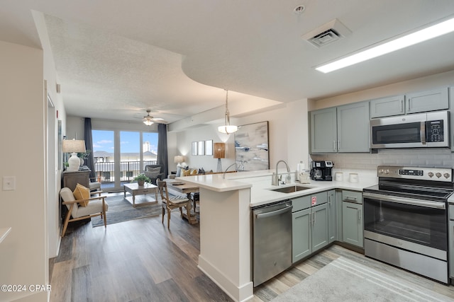 kitchen featuring light hardwood / wood-style floors, stainless steel appliances, sink, kitchen peninsula, and ceiling fan