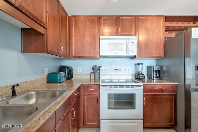 kitchen with light stone counters, sink, and white appliances